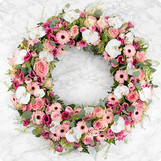 Cette couronne de deuil est composée de délicates fleurs de saison, soigneusement sélectionnées dans des tons roses et blancs pour offrir un camaïeu emprunt de douceur.